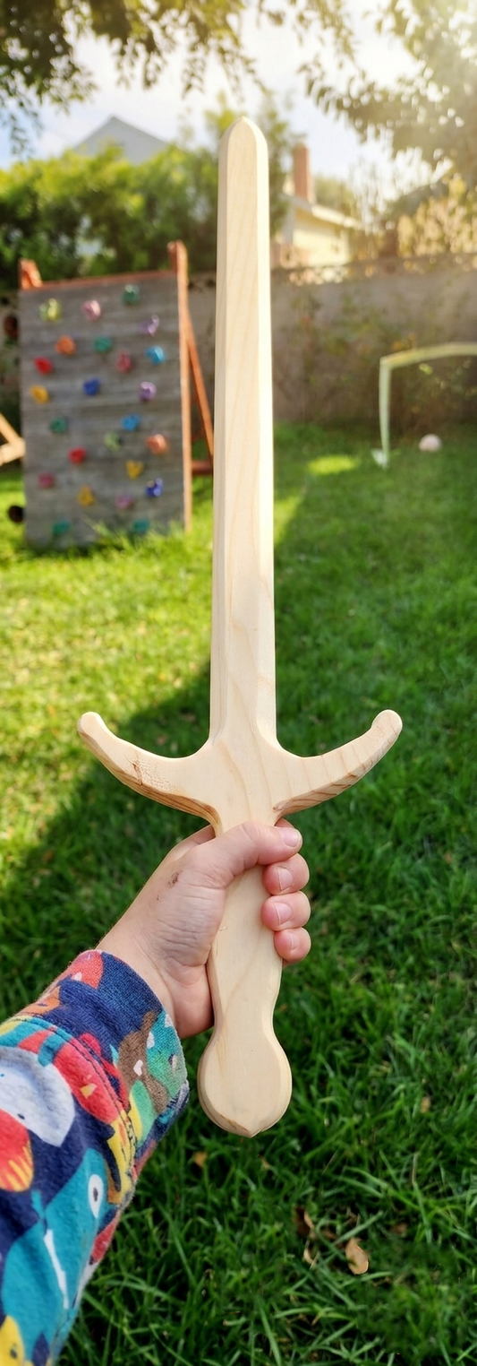 Hand holding a wooden sword in a grassy outdoor area